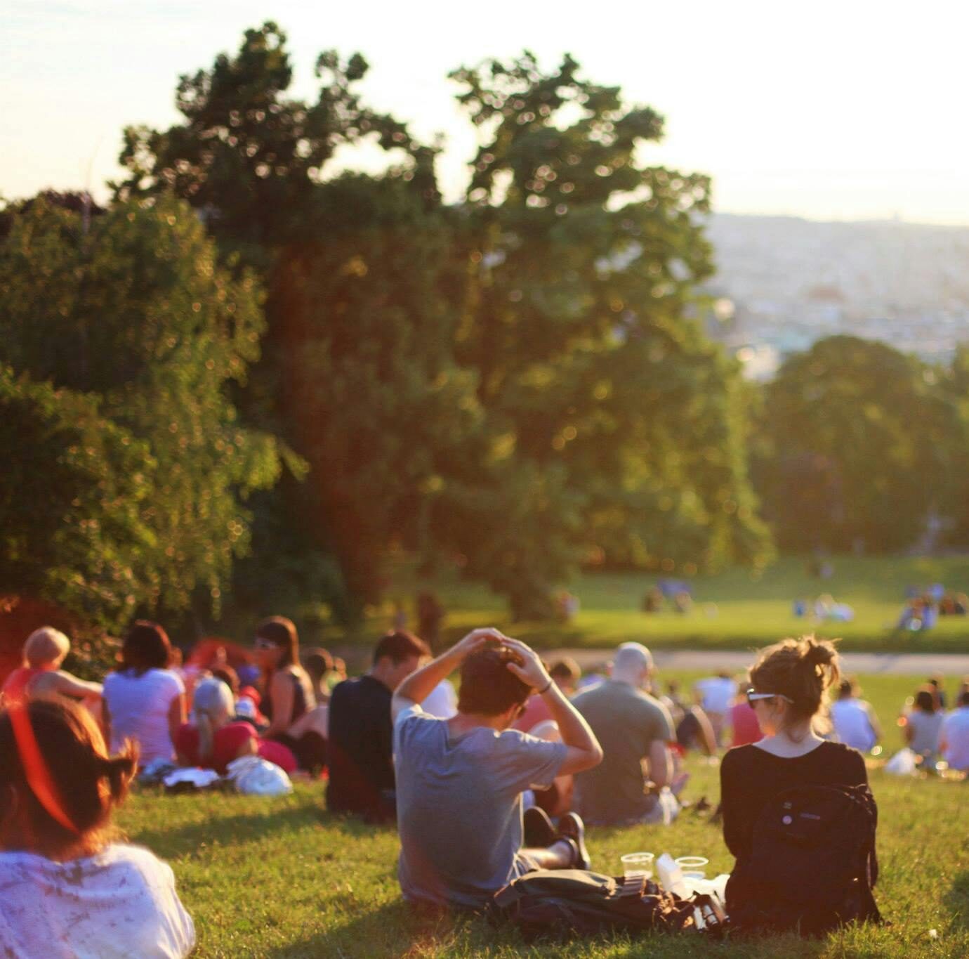 People relaxing and enjoying a sunny day in a bustling city park.